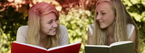 Imagine cu două tinere care citesc o carte. Fotografia ilustrează numeroasele mituri asociate menstruaţiei.